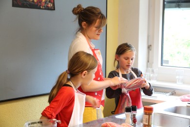 Eine Freiwillige zeigt Kindern wie man kocht.
