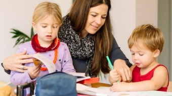 Eine Betreuerin hilf zwei Kindern bei den Hausaufgaben