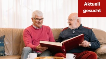 Zwei ältere Männer schauen gemeinsam in ein Buch.