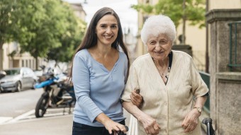 Eine Person begleitet eine ältere Frau bei einem Spaziergang