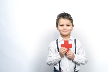 Junge hält ein rotes Kreuzchen
