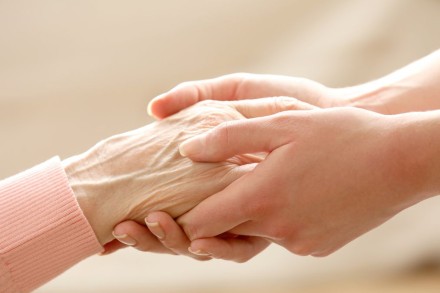 Eine Freiwillige hält die Hand einer älteren Person