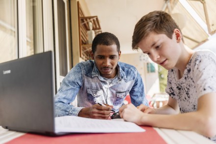 Ein Jugendlicher hilf einem asylsuchenden jungen Mann beim Lernen