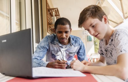 Ein Jugendlicher hilf einem asylsuchenden jungen Mann beim Lernen